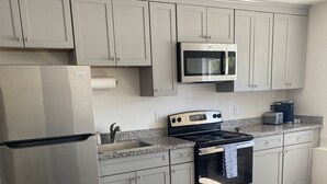 Una cocina moderna con armarios grises, electrodomésticos de acero inoxidable y una encimera de granito.