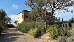 A gravel path leading to a building with a balcony, surrounded by greenery and trees. - 3bedroom flat in Les Issambres Var, superb sea view, pool and air conditioning (Roquebrune-sur-Argens)