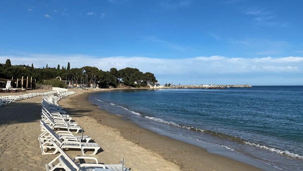 A beach with rows of white lounge chairs along the shore, a clear blue sky, and a calm sea. - 3bedroom flat in Les Issambres Var, superb sea view, pool and air conditioning (Roquebrune-sur-Argens)