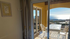 A balcony with a table and chairs, a bed with a blue mattress, and a view of a cityscape. - 3bedroom flat in Les Issambres Var, superb sea view, pool and air conditioning (Roquebrune-sur-Argens)
