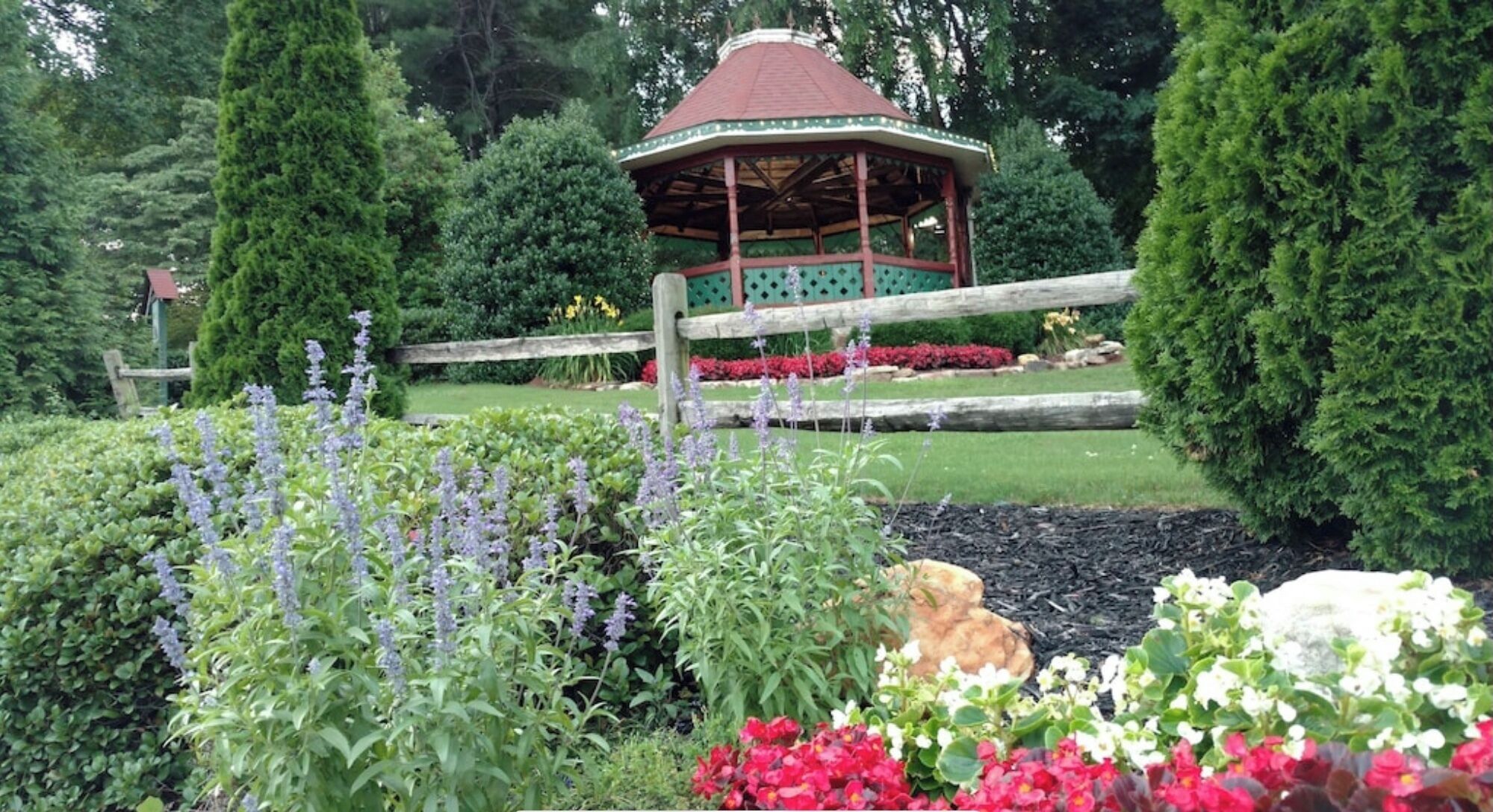 Un kiosque dans un jardin agrémenté de diverses plantes et fleurs.