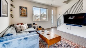 Ein modernes Wohnzimmer mit einer Couch, einem Couchtisch und einem an der Wand befestigten Flachbildfernseher.