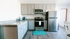 A kitchen with light grey cabinets, a stainless steel refrigerator, a microwave, and a stove. - Cozy 2 Bedroom with Full Kitchen One Block from the Ocean!! (Crescent City)