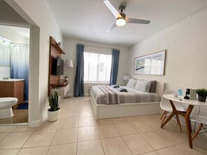 Relax in a serene bedroom with a large bed, ceiling fan, and a window with a view.
