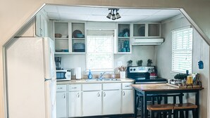 A compact kitchen with white cabinets, a refrigerator, and a dining area with a table and chairs. - Mountain Cottage with Private Views and Hot Tub!! (Shenandoah)