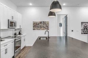 Una cocina moderna con armarios blancos, electrodomésticos de acero inoxidable y una isla grande con fregadero.