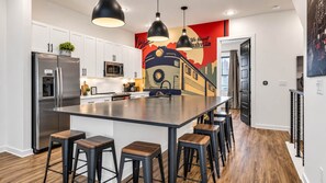 A modern kitchen with a central island, stainless steel appliances, and bar stools. - Highland Station • Rooftop Views • Sleeps 14 (Nashville)