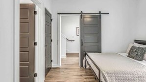 Ein Schlafzimmer mit Bett, einer Schiebetür und einer Treppe, die in einen anderen Raum führt.