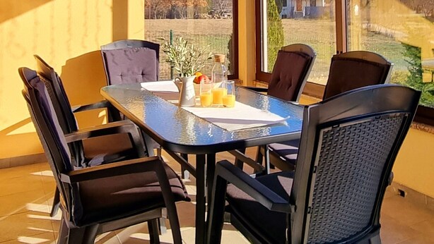 A dining area with a glass table and chairs, a pitcher of orange juice, and a view of the outdoors. - Comfortable single family home on the east coast of Istria peninsula (Štrmac)