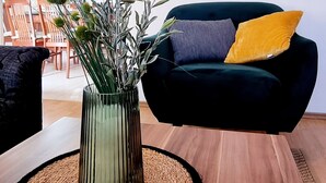 A living room with a dark green sofa, a yellow pillow, and a vase with green plants on a wooden table. - Comfortable single family home on the east coast of Istria peninsula (Štrmac)