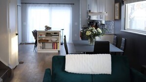 A modern living room with a green sofa, a dining area with a table and chairs, and a kitchen with cabinets and a window. - Funky Modern Home Minutes Drive from Downtown CLE (Cleveland)