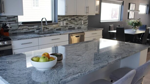 A modern kitchen with a granite countertop, a bowl of fruit, and a dishwasher. - Funky Modern Home Minutes Drive from Downtown CLE (Cleveland)