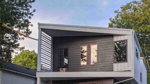 A modern two-story house with a flat roof, a front porch, and a visible garage. - Funky Modern Home Minutes Drive from Downtown CLE (Cleveland)