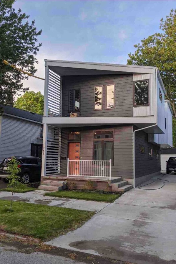 A modern two-story house with a flat roof, a front porch, and a visible garage.