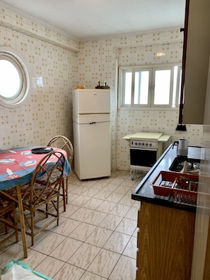 Compact kitchen with basic amenities, including a refrigerator, stove, and dining area.