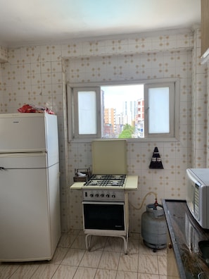 Enjoy cooking in this kitchen with a gas stove, microwave, and refrigerator, offering a city view.