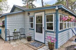 A small house with a porch, two chairs, a table, and potted plants. - Historic Cottage on White Pond, near Downtown Chatham and beaches (Chatham)