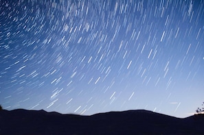 A star trail photograph with a mountain silhouette in the foreground.