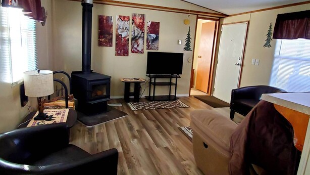 A cozy living room with a wood-burning stove, a flat-screen TV, and a comfortable seating area. - Iron Wolf nestled in the Sangre de Cristo Mtns...Ski/Hike/Fish/Hunt Casita (Eagle Nest)