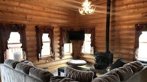 A log cabin interior with a sofa, a fireplace, and a television. - Log Home on the Blackfoot River (Lincoln)