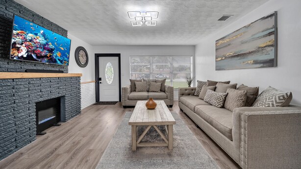 Ein Wohnzimmer mit Kamin, Fernseher, Sofa und Couchtisch.