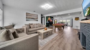 Ein modernes Wohnzimmer mit einer Couch, einem Couchtisch und einem Billardtisch.