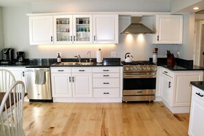 A modern kitchen with white cabinets, a stainless steel stove, and a black countertop.
