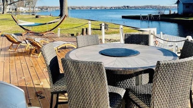 Um terraço com móveis de vime e vista para um lago.
