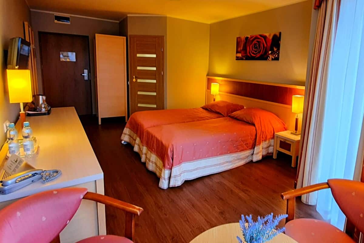 Ein Hotelzimmer mit einem Bett, Nachttischen, einem Schreibtisch mit Telefon und einem Sessel.