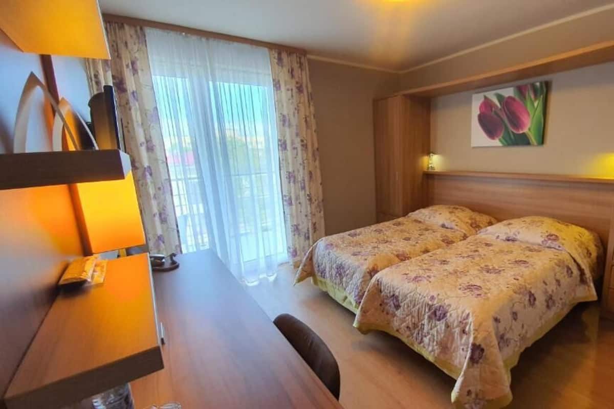 Ein Schlafzimmer mit zwei Betten, einem Holztisch und einem Bild an der Wand.