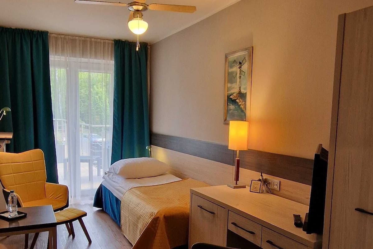 Ein Hotelzimmer mit Bett, Schreibtisch, Stuhl und Blick ins Freie.