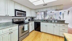 Una cocina moderna con armarios blancos, electrodomésticos de acero inoxidable y tragaluces.