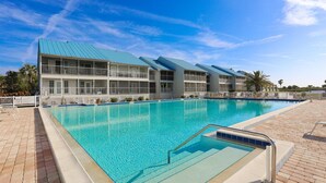 Un hotel con una piscina grande, varios balcones y un cielo azul despejado.