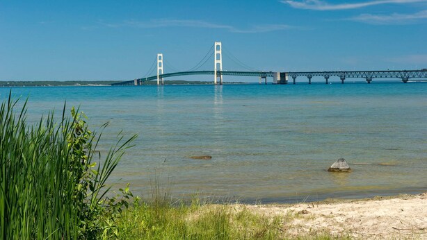 A bridge over a calm body of water with a sandy beach in the foreground. - Charming Historic Mackinaw City Cottage (Mackinaw City)