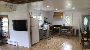 A compact kitchen with white cabinetry, a built-in oven, a refrigerator, and a sink. - Charming Historic Mackinaw City Cottage (Mackinaw City)