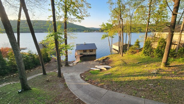 A lakeside property with a dock, a small house, and a paved pathway. - Honeycomb Waterfront Lakehouse with deep water dock (Grant)