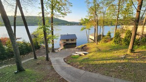 A lakeside property with a dock, a small house, and a paved pathway. - Honeycomb Waterfront Lakehouse with deep water dock (Grant)
