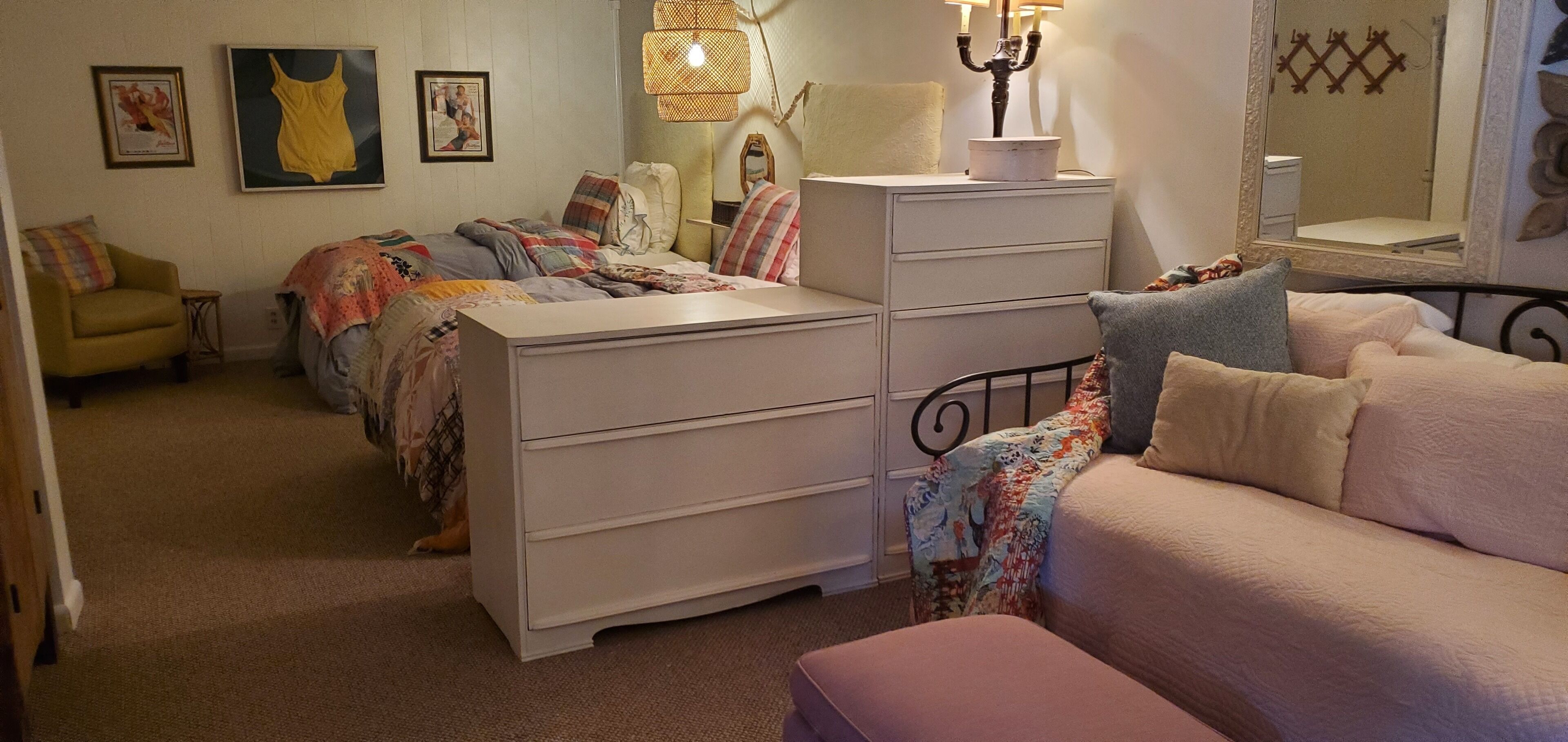 Un dormitorio con cama, cómoda, silla y espejo.