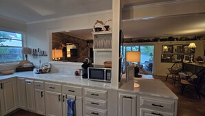 A modern kitchen with white cabinetry, a central island, and a stone accent wall. - Honeycomb Waterfront Lakehouse with deep water dock (Grant)