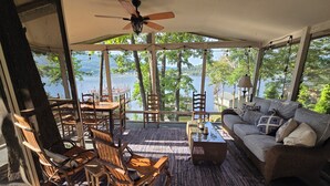 A covered outdoor seating area with a table and chairs, a sofa, and a ceiling fan. - Honeycomb Waterfront Lakehouse with deep water dock (Grant)