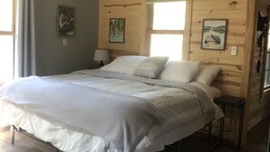 Ein Schlafzimmer mit einem großen Bett, Holzwänden und einem Deckenventilator.