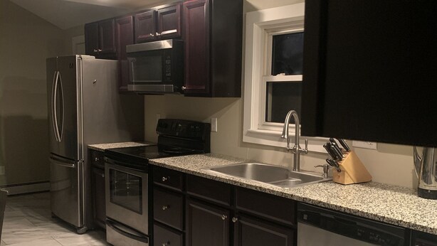 A modern kitchen with dark cabinets, stainless steel appliances, and granite countertops. - Cozy 3 bedroom house , pet friendly , yard (Portsmouth)