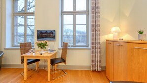 Ein gemütlicher Essbereich mit Holztisch, zwei Stühlen, einer Blumenvase und einem Hausgemälde an der Wand.