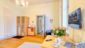 Ein Hotelzimmer mit Holzboden, einem Esstisch mit Blumenvase, einer Fernbedienung und einem gerahmten Bild an der Wand.