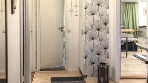 A hallway with a door leading to a room, a patterned wall, and a trash bin. - 2 bedroom cozy home in Ramdala (Ramdala)