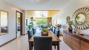 A modern dining area with a long table, chairs, and a ceiling fan.