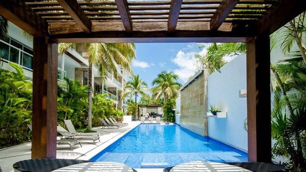A pool area with lounge chairs and a pergola structure.