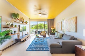 A modern living room with a sofa, coffee table, and decorative items on shelves.