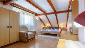 Een slaapkamer met een houten plafond, een bed, een stoel en een nachtkastje met lampen.