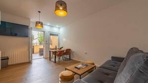 Een moderne woonkamer met een grijze bank, een houten salontafel, en een eethoek met stoelen en een tafel.